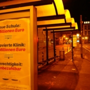 Ein Plakat hängt im Dunklen in einer Werbefläche einer Straßenbahnhaltestelle