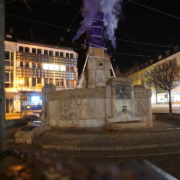 Vor der Verhüllten Bismarckstatue zünden zwei Menschen lila Rauch auf den Leitern