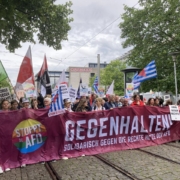 Schräges Foto des Fronttranspies mit der Aufschrift Gegenhalten - Solidarisch gegen rechte Hetze der AfD. Dahinder viele Menschen mit Fahnen.