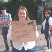 Eine Aktivistin hält ein Schild mit dem Slogan "1984 war keine Anleitung"