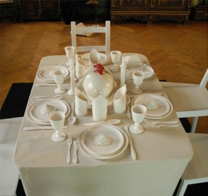 Ein gedeckter Tisch mit Stühlen darum, aus Keramik.
