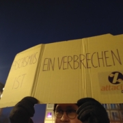 Ein Mann hält ein Pappschild hoch mit der Aufschrift: Rasissmus ist ein Verbrechen
