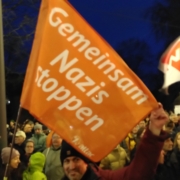 Ein Aktivist hält eine Fahne mit der Aufschrift "Gemeinsam Nazis stoppen"