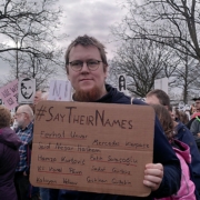 Ein Aktivist hält ein Schild mit #SayTheirNames und den Namen der Opfer