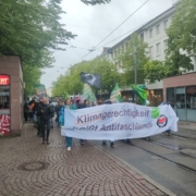 Die Demospitze läuft mit einem Fronttransparent mit dem Slogan "Klimagerechtigkeit heißt Antifaschismus" über die Rheinstraße auf den Lui