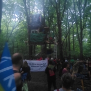 Vor einem Baumhaus der Waldbesetzung stehen mehrere Aktivist*innen