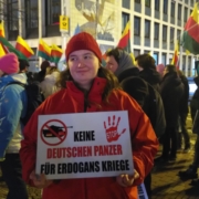 Eine Demonstrantin hält ein Schild mit der Aufschrift "Keine deutschen Panzer für Erdogans Krieg!", hiner ihr ist die Demo auf dem Lui zu sehen
