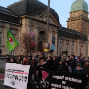 Vor dem Gebäude des Landesmuseums ist eine Menschenmenge mit Transpies und Fahnen.
