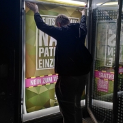 Ein Mann hängt ein Plakat in Bundeswehroptik auf.