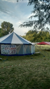 Bild vom Infozelt auf dem System Change Camp, am Zelt hängt ein Banner mit der Aufschrift "Willkommen beim schönen System Change Camp"