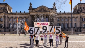 Vor dem Reichstagsgebäude halten Aktivist*innen in Tax-the-Rich-T-Shirts die Zahlen 67975 hoch