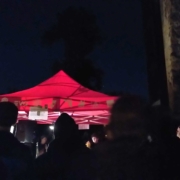 Ein beleuchteter, roter Pavillion in einer Menschenmasse.